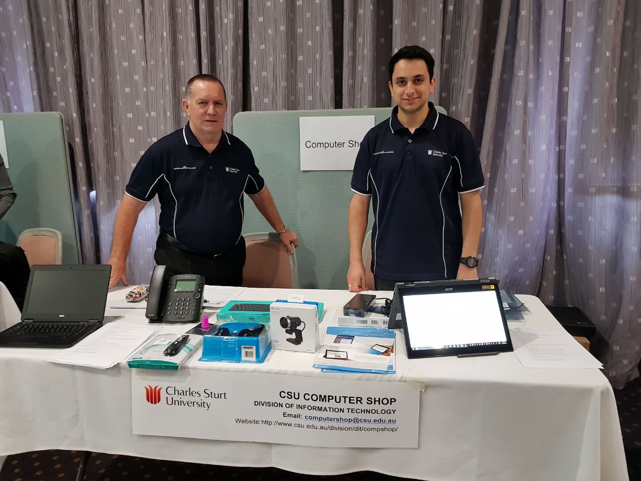 Cedric Locke and Ramin Ghorashi standing at the Computer Shop display at the Faculty of Science forum on Wagga Wagga campus