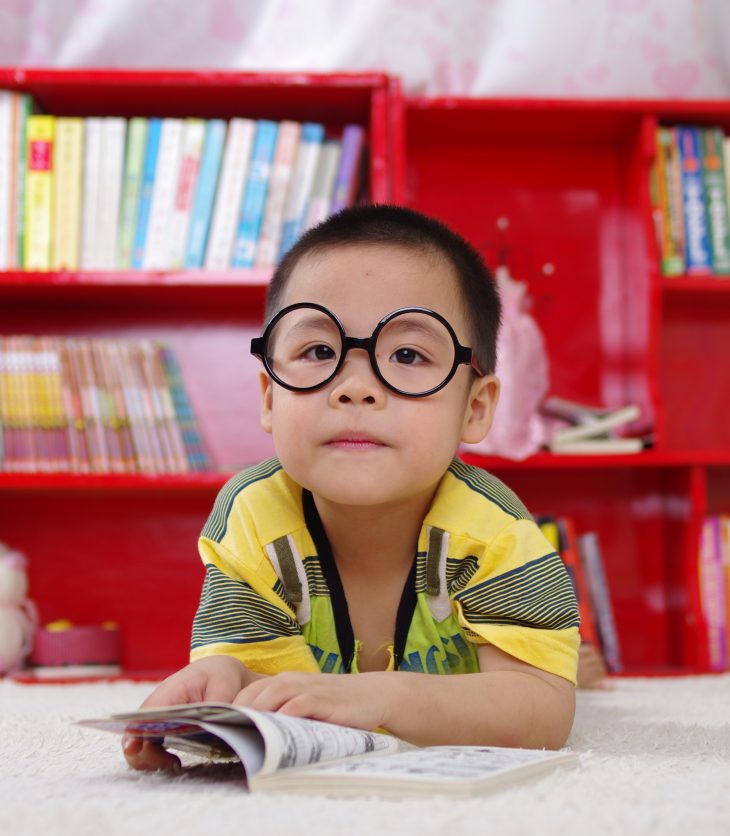 Boy with glasses in front of bookshelf